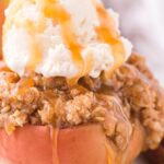 A baked red apple with oatmeal topping and ice cream on top.
