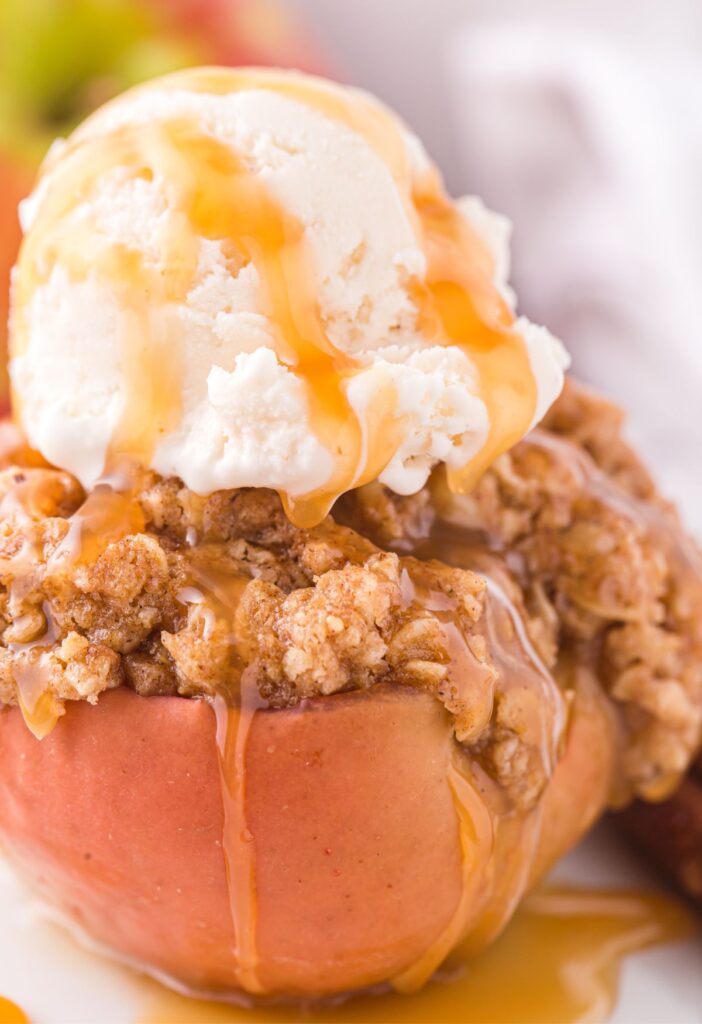 A baked red apple with oatmeal topping and ice cream on top. 