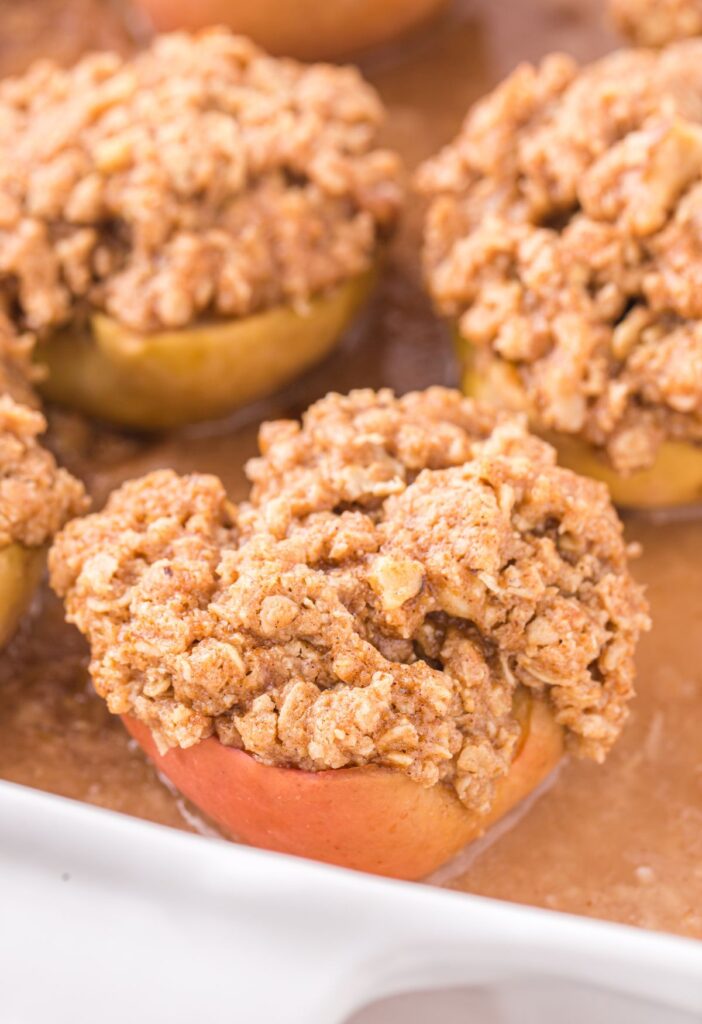 A baking pan of apples inside juice and topped with streusel. 