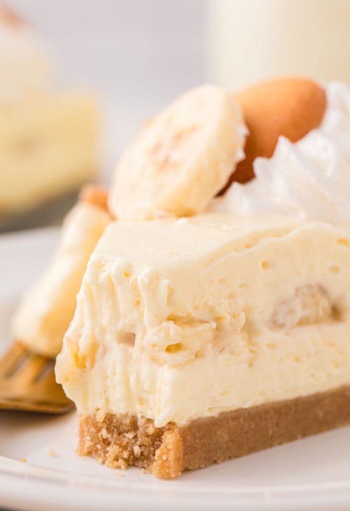 Close up of a piece of cheesecake with fresh bananas and banana pudding. 