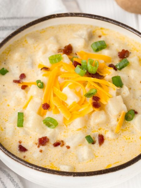 a bowl of chunky potato soup inside a bowl with toppings.