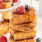 A stack of French toast rolls with berries and syrup.