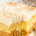 A slice of cake with a bite taken out of the front with a fork.