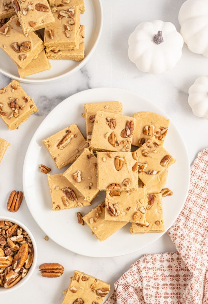 Overhead picture of a plate of pumpkin fudge with a towel and other things around it. 