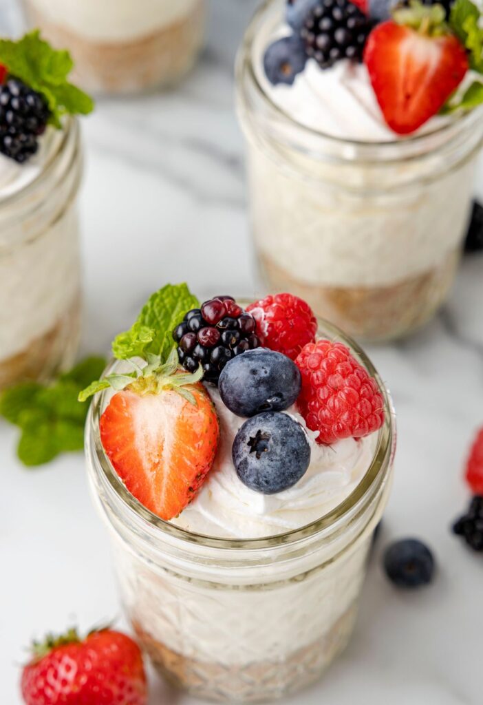 Berries on top of whipped cream inside jars. 