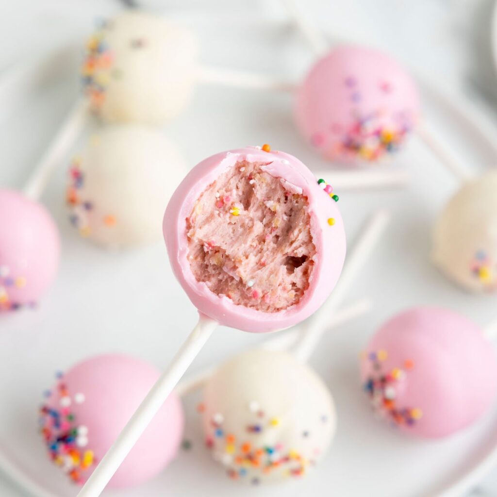 A cake pop with a bite taken out of it on a stick. 