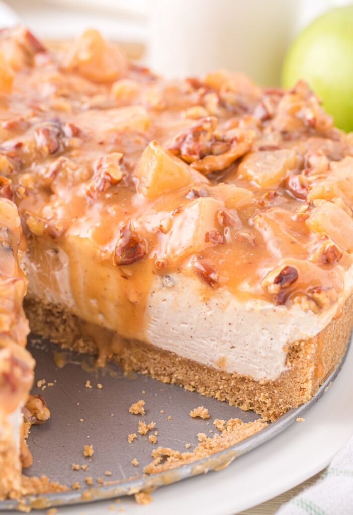 A springform pan of apple cheesecake with a piece gone. 