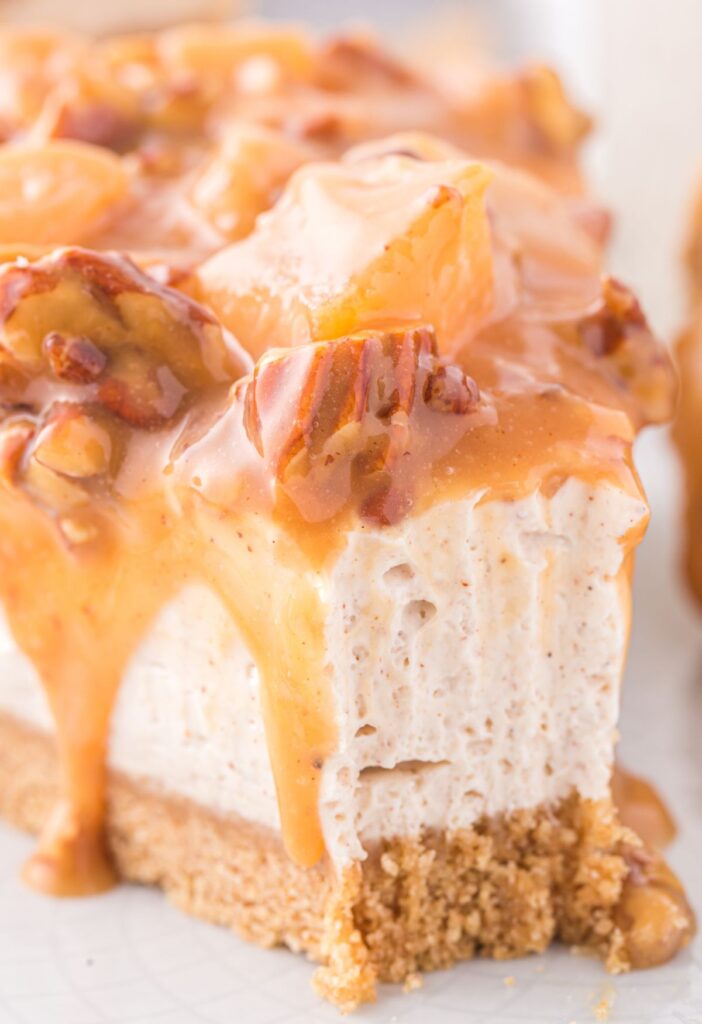 Slice of cheesecake with caramel running down the sides of it. 