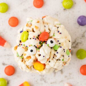 Overhead shot of a popcorn ball with candies around it.