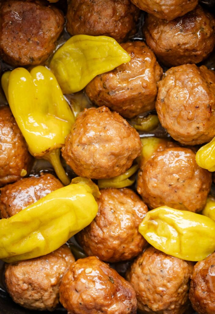 Close up picture of the cooked meatballs with pepperoncini peppers. 