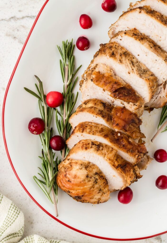 A plated cooked turkey breast with rosemary. 