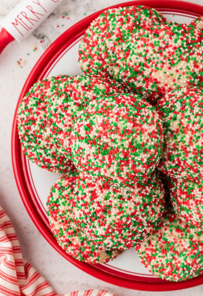 Cookies on a red plate with Christmas decor around it. 