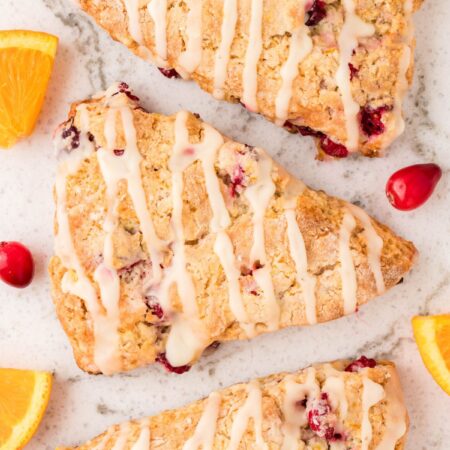 Three scones in a row with cranberry and oranges slices.