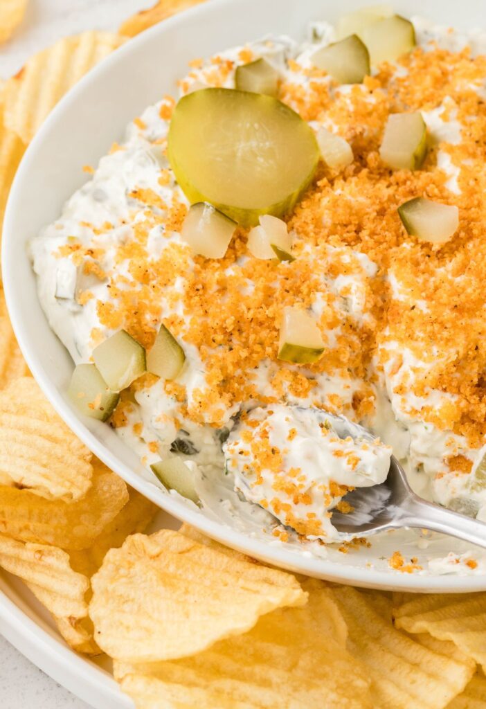A bowl of dip with wavy potato chips around it