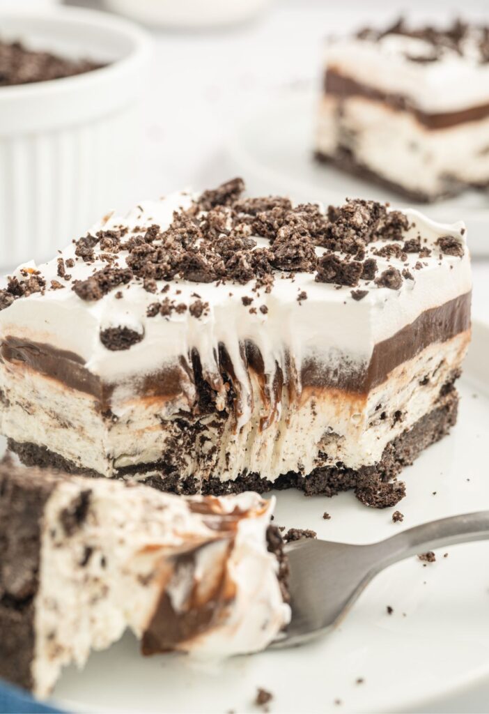 A slice of oreo delight with a fork bite taken out of the front of it. 