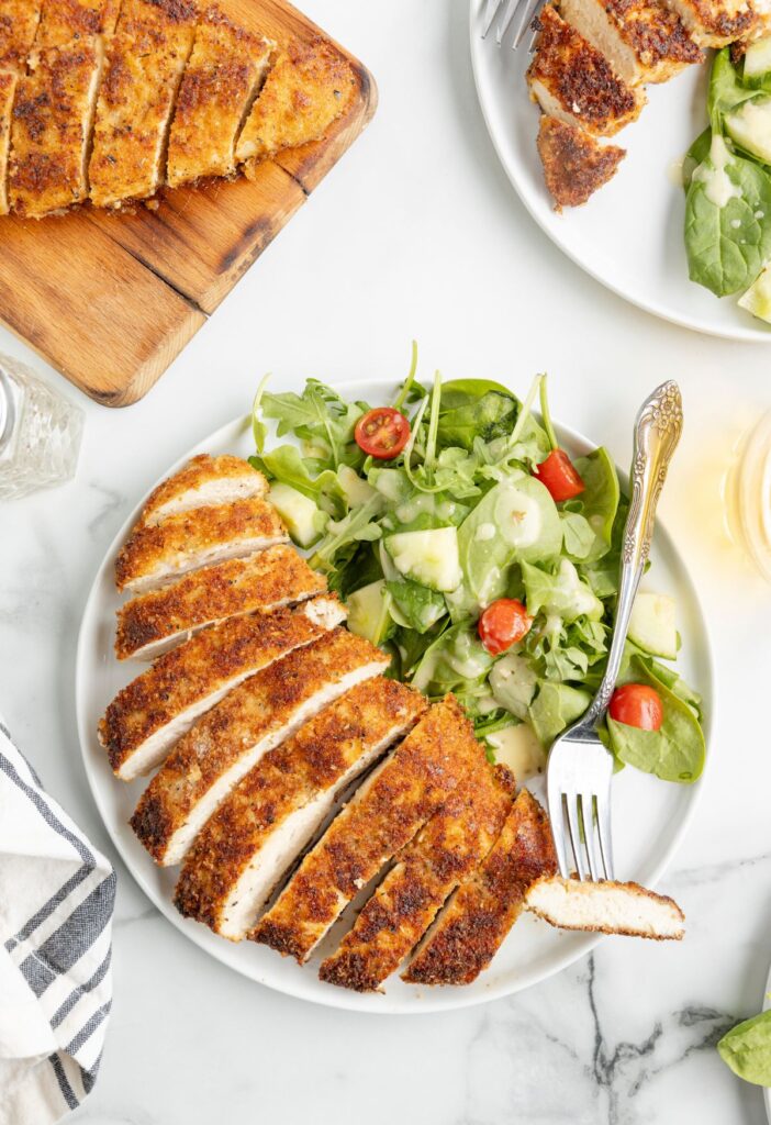 Overhead shot of a serving plate of chicken with salad. 