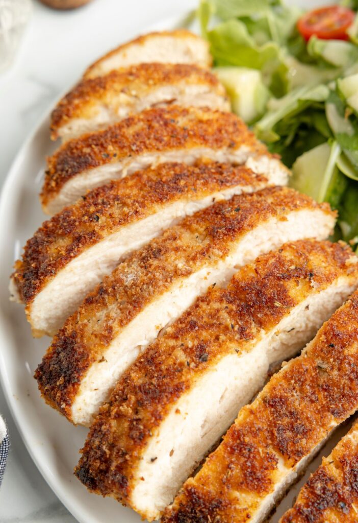 Sliced chicken on a plate with salad