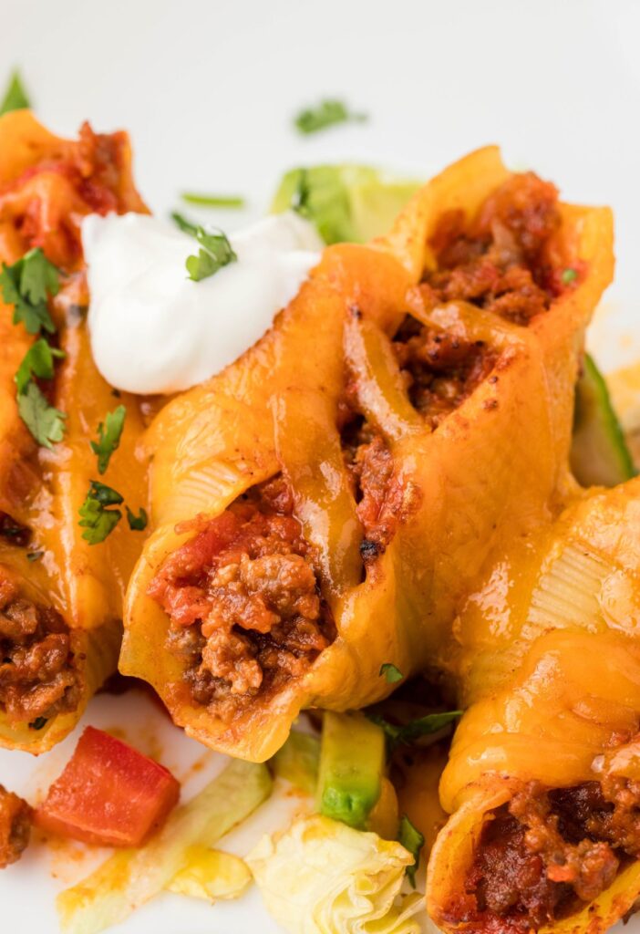 A serving plate of taco stuffed shells with taco toppings. 