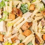 Close up off the top of the bowl of pasta salad with lettuce, chicken, and caesar dressing.