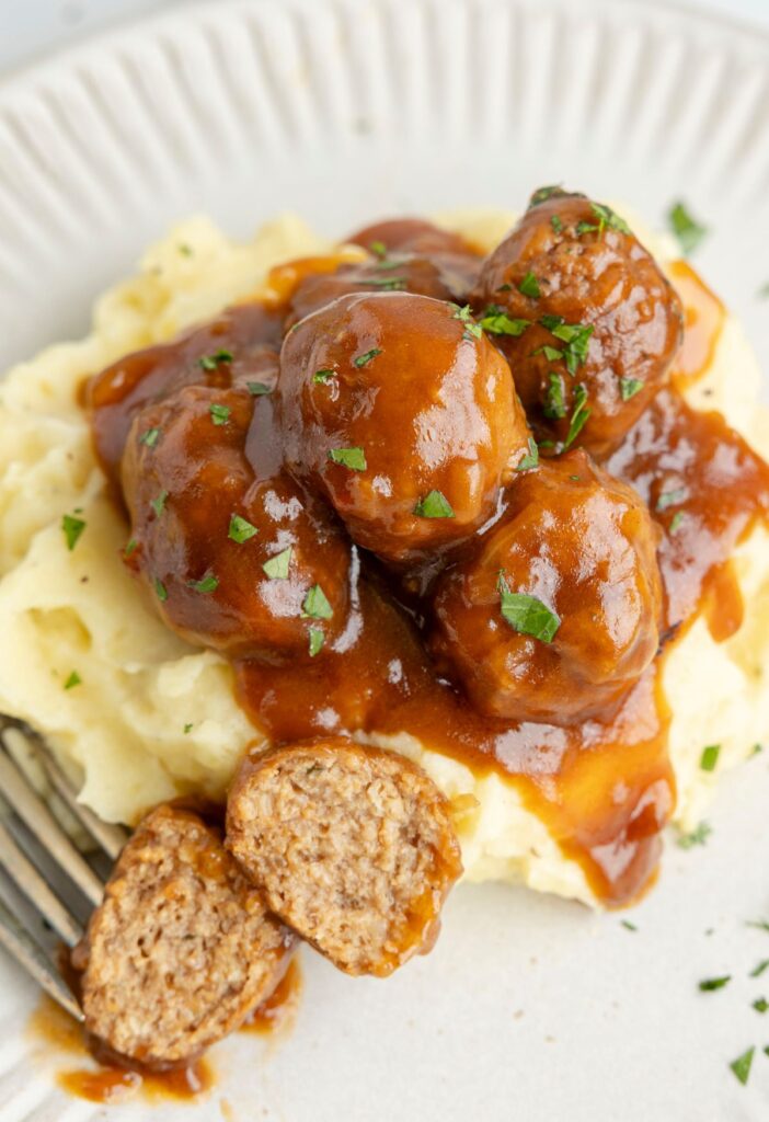 mashed potatoes with gravy meatballs over top and a fork. 