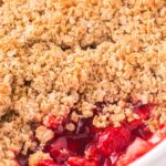 A crumble dessert inside a white pan with the corner scooped out.