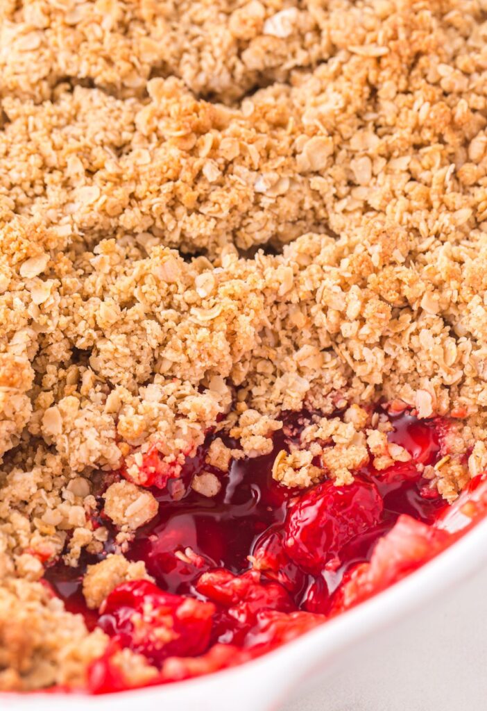 A crumble dessert inside a white pan with the corner scooped out. 