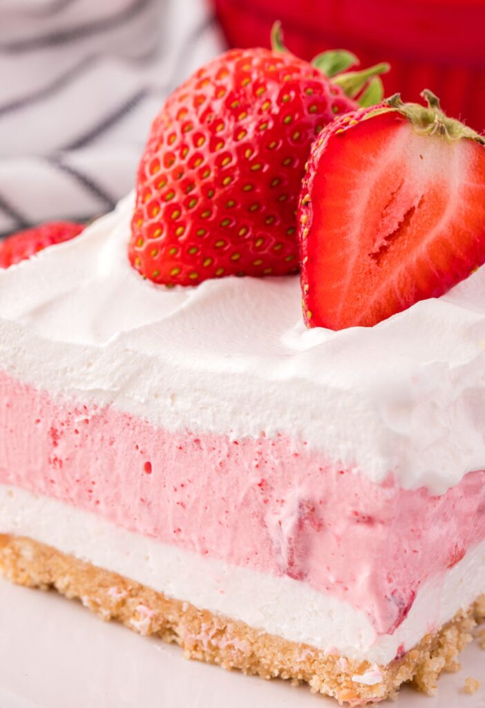 Slice of layered dessert topped with strawberries.