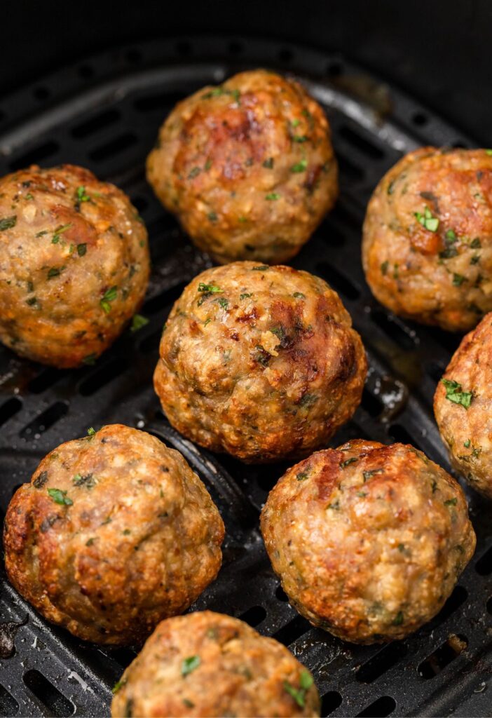 Cooked meatballs inside the air fryer basket. 