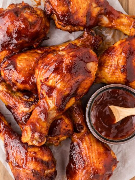 A pile of drumsticks with bbq sauce on them.