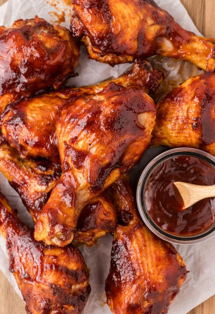 A pile of drumsticks with bbq sauce on them. 