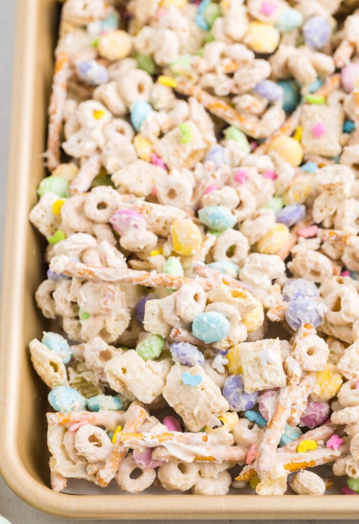 A cookie sheet of the snack mix with white chocolate and sprinkles. 