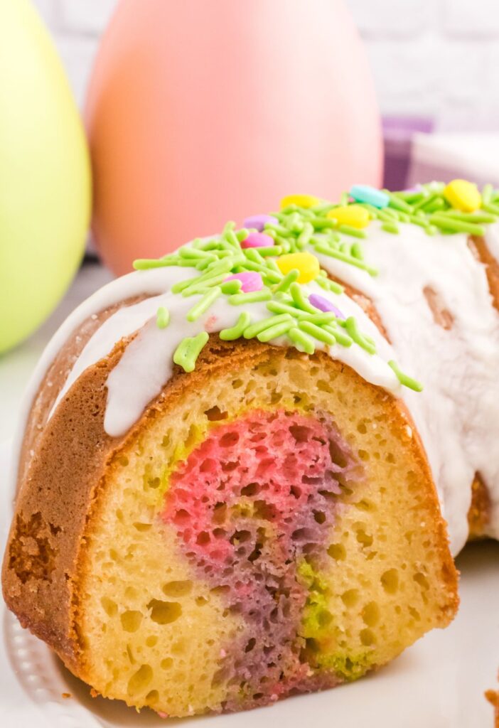 Side view of the bundt cake with plastic eggs in the background