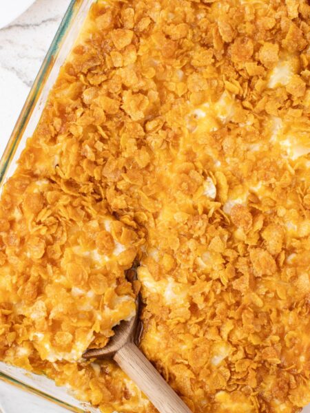 A casserole pan of cheesy potatoes with corn flake topping.