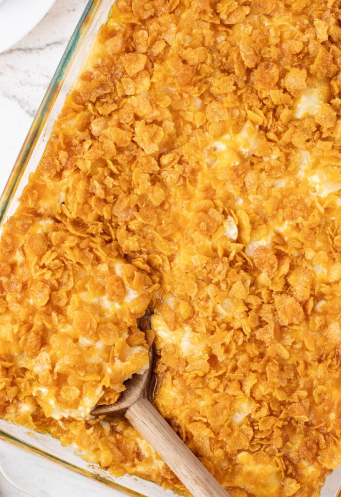 A casserole pan of cheesy potatoes with corn flake topping. 