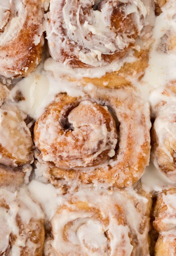 Close up shot of the tops of the baked cinnamon buns inside a pan. 