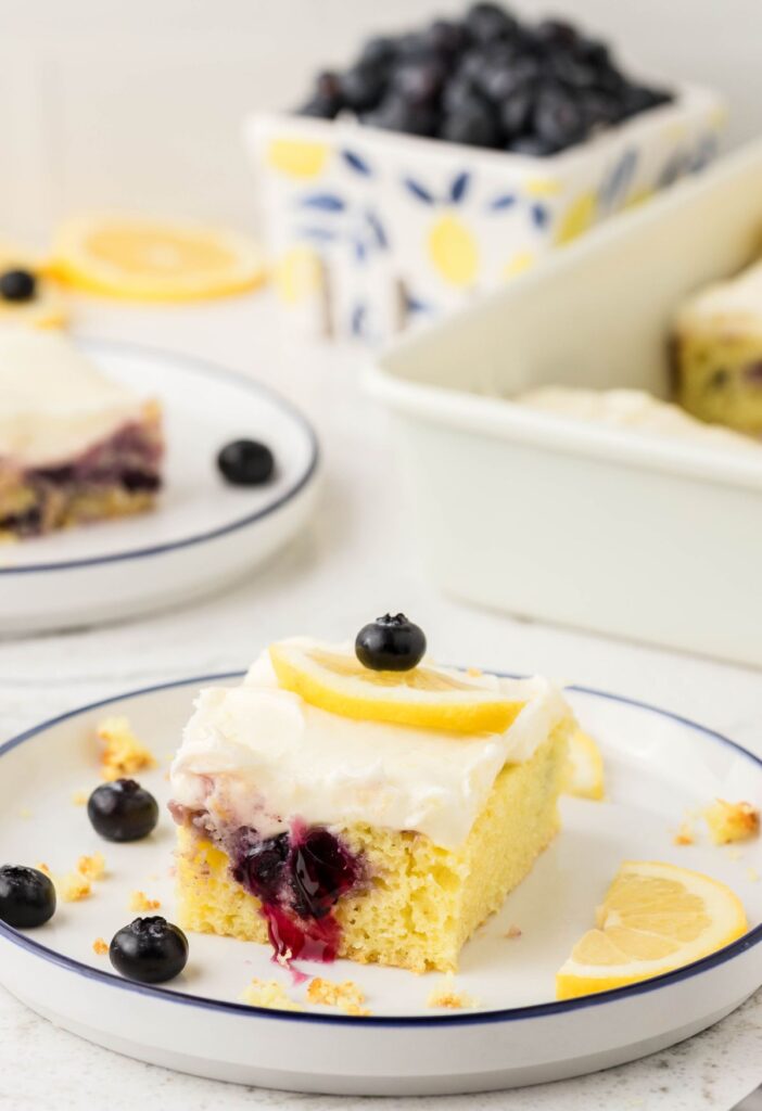 A slice of cake with the cake pan in the background and fresh blueberries. 