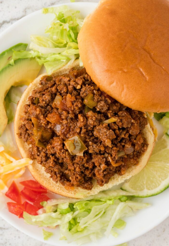 Overhead pic of the sloppy Joe with toppings beside it.
