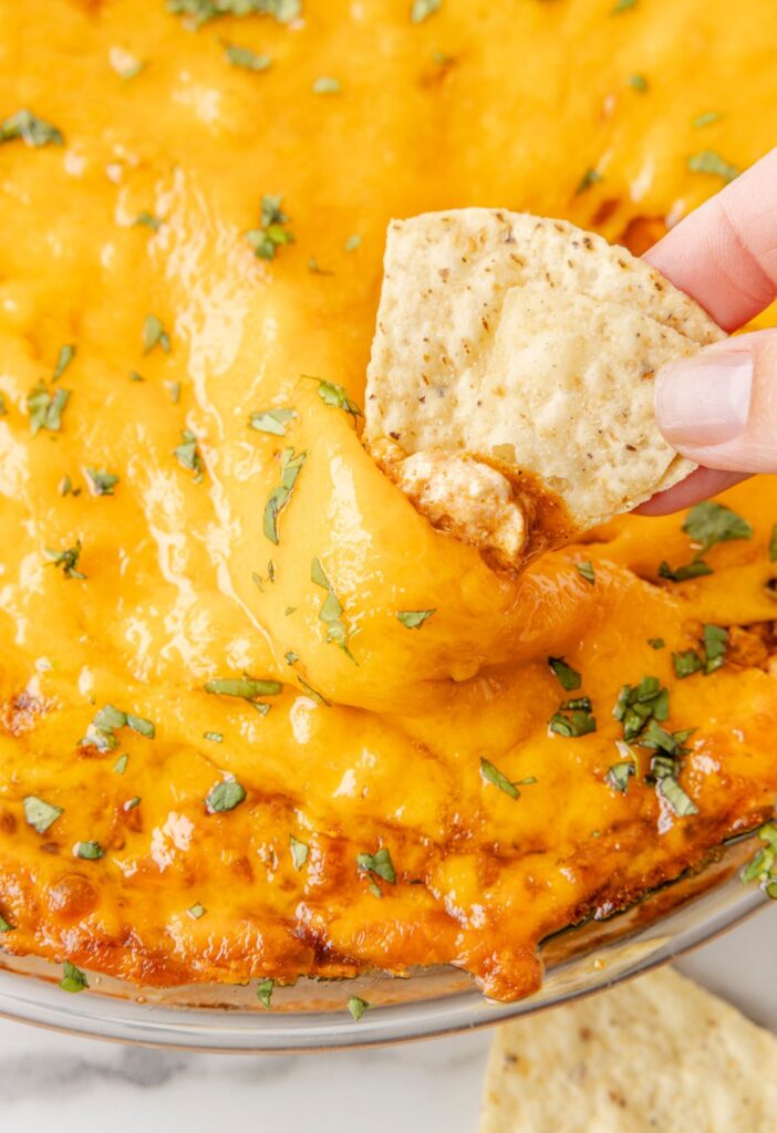 Close up of the cheesy dip with a chip being dipped into it. 