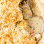 A pot pie with biscuit topping and a spoon inside of it.