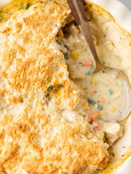 A pot pie with biscuit topping and a spoon inside of it.