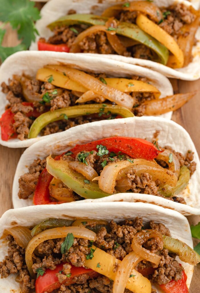 Line of flour tortillas with ground beef fajita mix inside. 