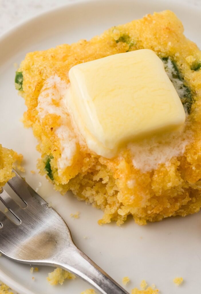 A slice of cornbread with a melted piece of butter on top. 