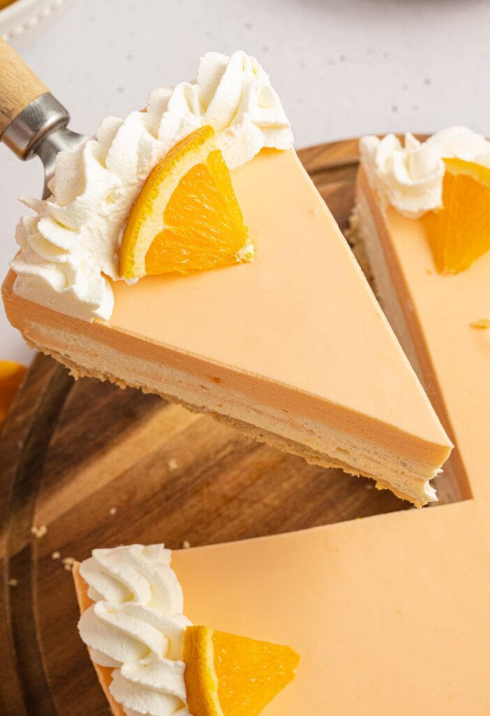 A slice of cheesecake with a fresh orange slice on top. 