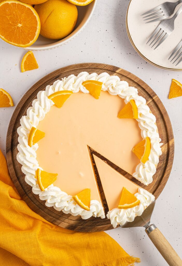 Whole cheesecake with a slice out of it with a serving spatula. 