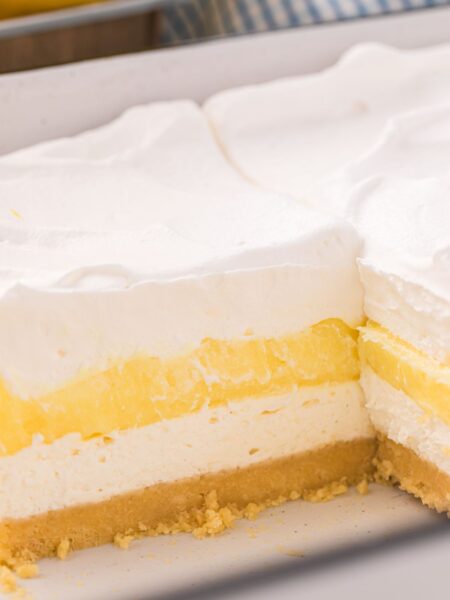 A pan of the lemon lush dessert with a piece gone to show the layers