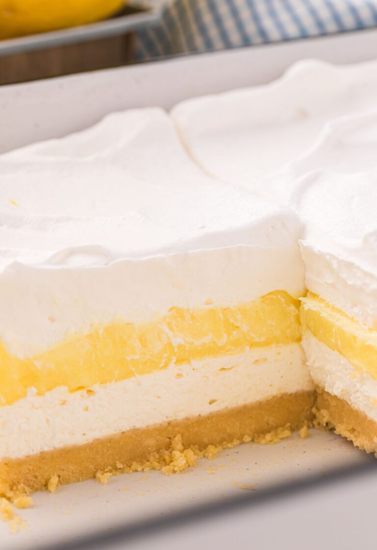 A pan of the lemon lush dessert with a piece gone to show the layers