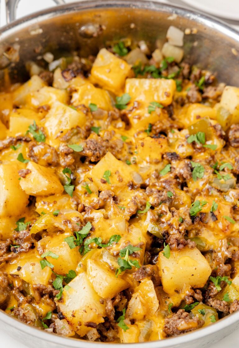 A skillet pan with beef and potatoes in it and cheese.