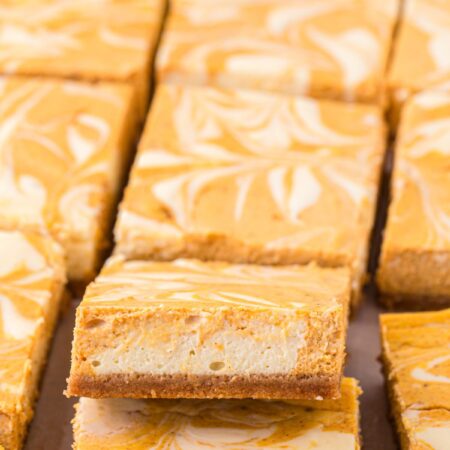 A row of cheesecake bars with one tilted up to see the middle.