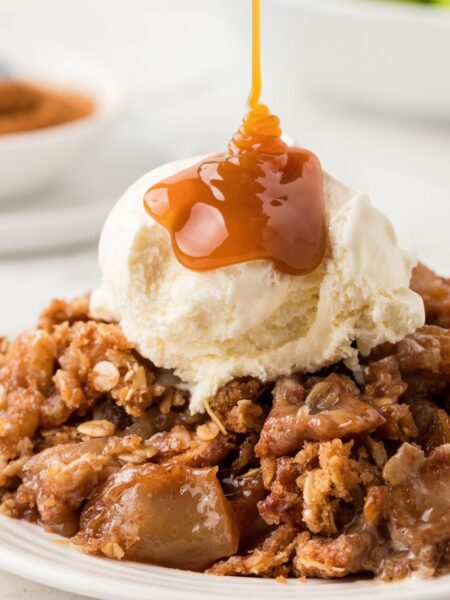 Apple fruit crisp with ice cream and a caramel drizzle coming over top