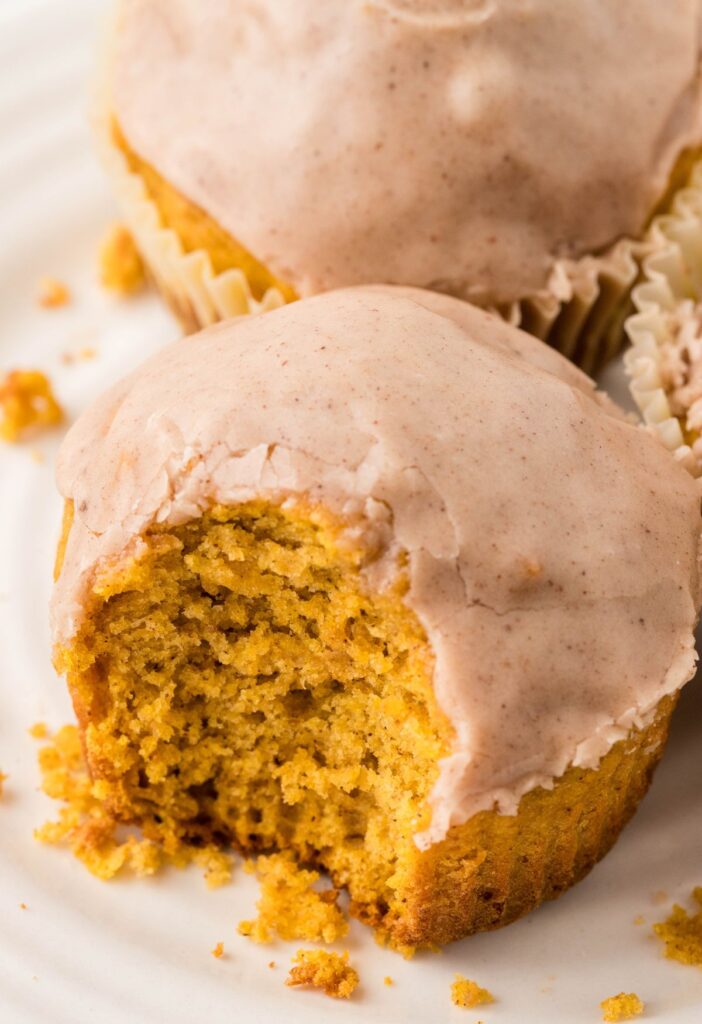 View of a donut muffin with pumpkin with a bite taken out of it.